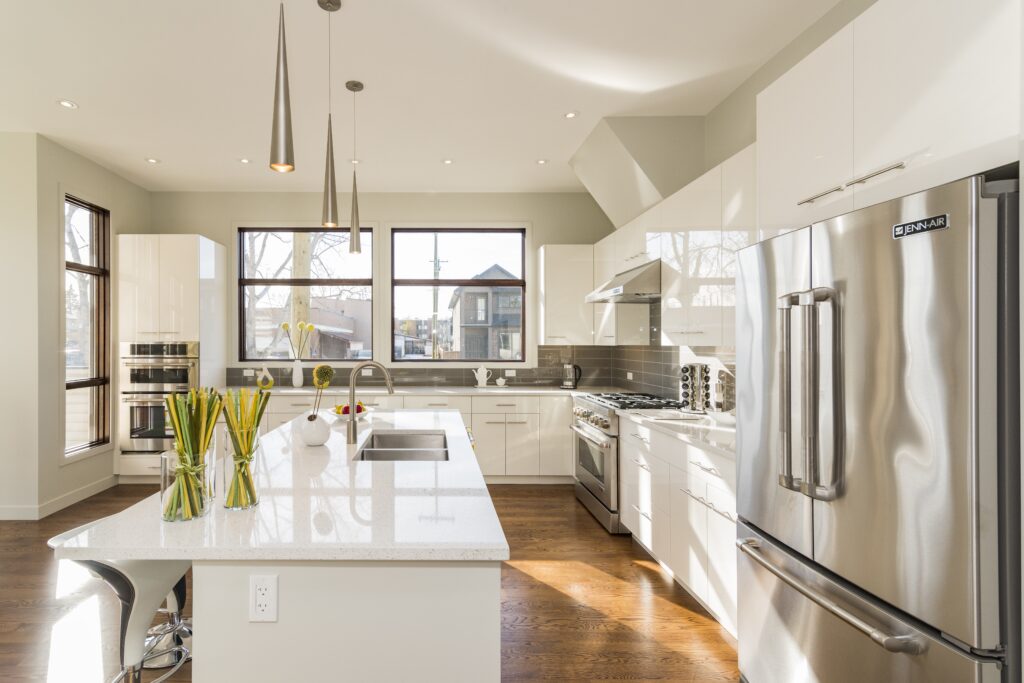 Modern kitchen interior with natural light, white countertops, and stainless steel appliances.